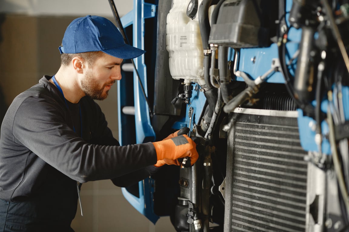 Man in Black Long Sleeve Shirt Repairing Blue Machine